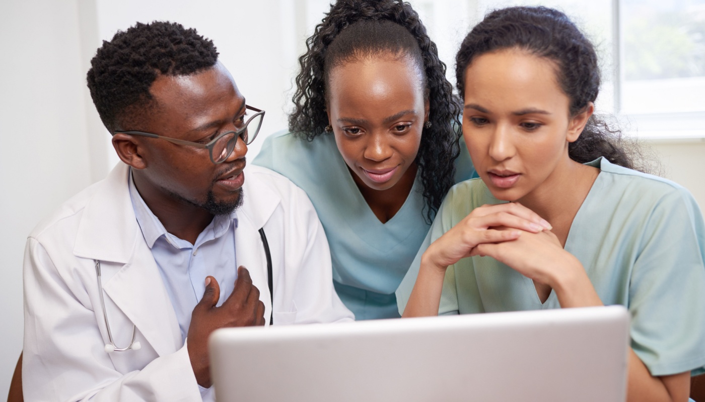 Three doctors look at laptop, reviewing data; KOL relationships concept