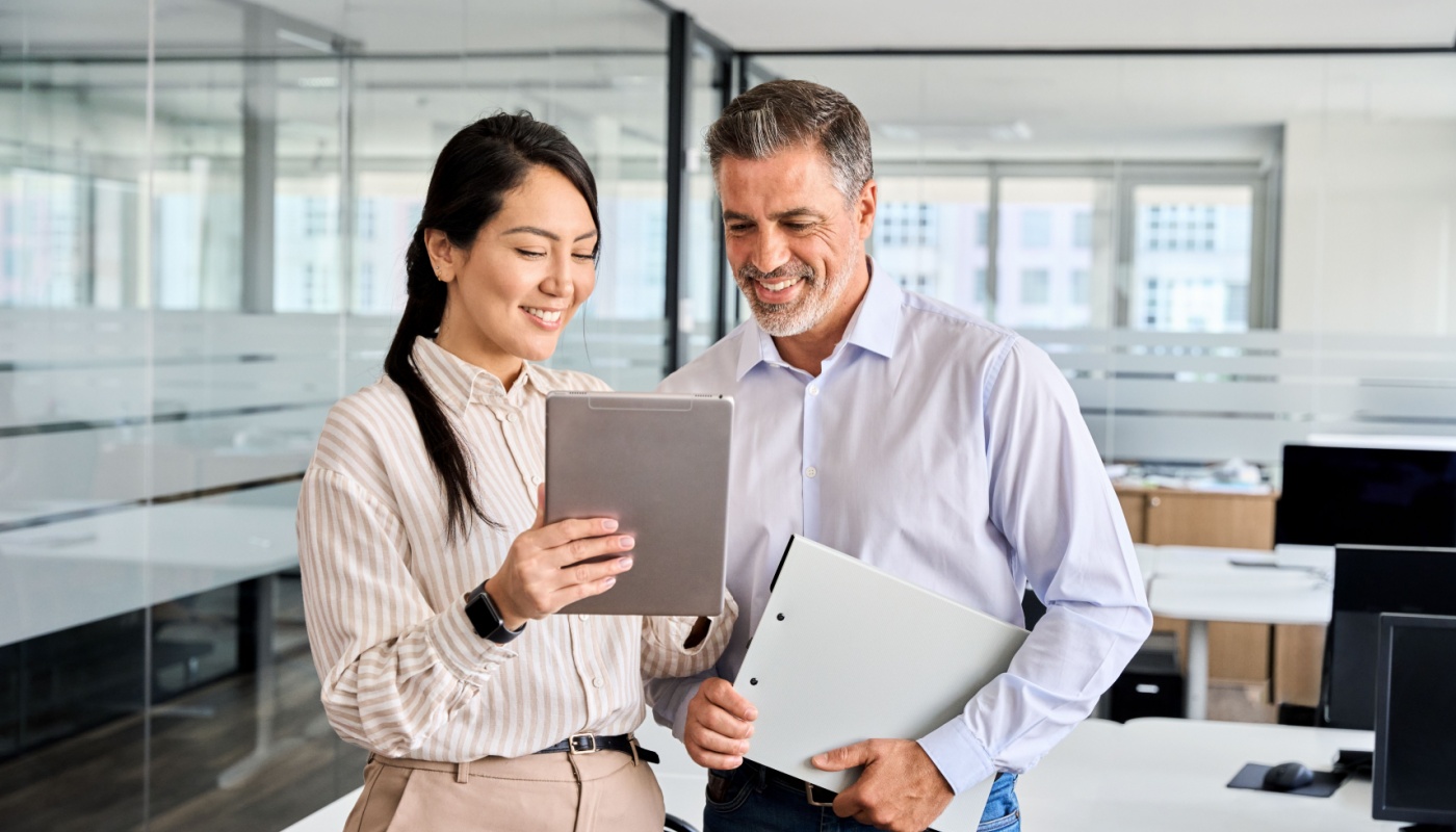 Colleagues smiling and looking at tablet; clinical trial financial management concept